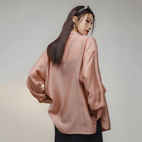 Woman wearing a sheer pink blouse against a plain background